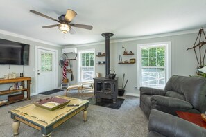 A cozy living room with a fireplace, a television, and a comfortable sofa. - Little Rock Creek Cottage on Trout Stream (Bakersville)