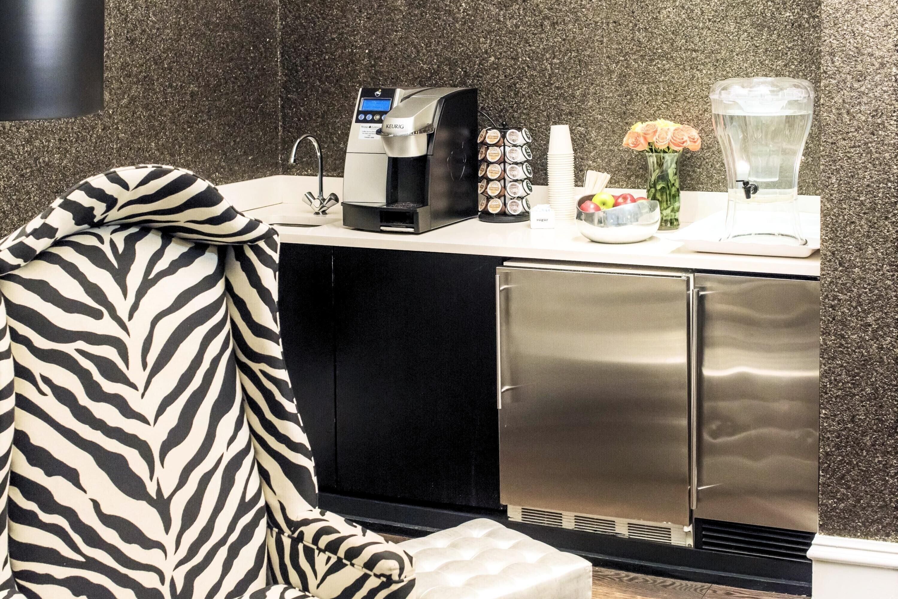 A kitchenette with a coffee maker, sugar, and a fruit bowl.
