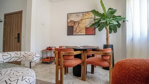 Una sala moderna con comedor, una planta grande y un cuadro en la pared.