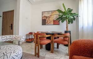 Ein modernes Wohnzimmer mit Essbereich, einer großen Pflanze und einem Gemälde an der Wand.