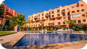 Un hotel con piscina, varios balcones y palmeras.