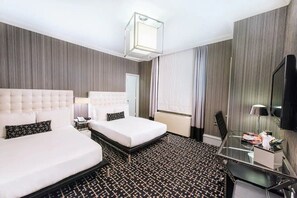 Een hotelkamer met twee bedden, een bureau, een flatscreen-tv en een moderne kroonluchter.