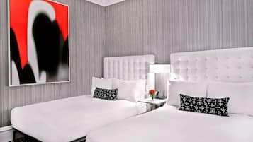 Habitación de hotel con dos camas, un cuadro abstracto moderno y una mesita con una lámpara.