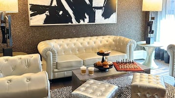 Una sala de estar moderna con un sofá capitonado, una mesa de centro con pasteles y un tablero de ajedrez.