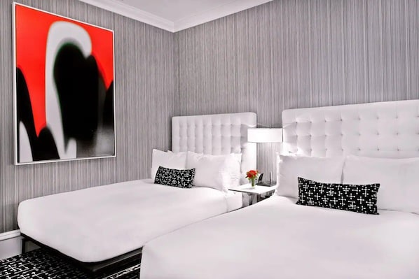 Ein Hotelzimmer mit zwei Betten, einem modernen abstrakten Gemälde und einem kleinen Tisch mit einer Lampe.