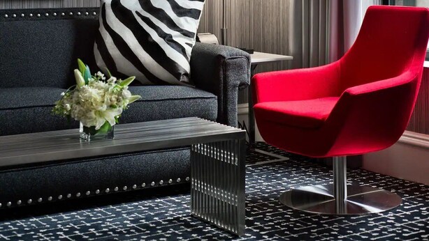 A modern living area with a sofa, a red chair, and a coffee table. - Moderne | Junior Suite | Steps to Times Square | Extra Living Space (New York)