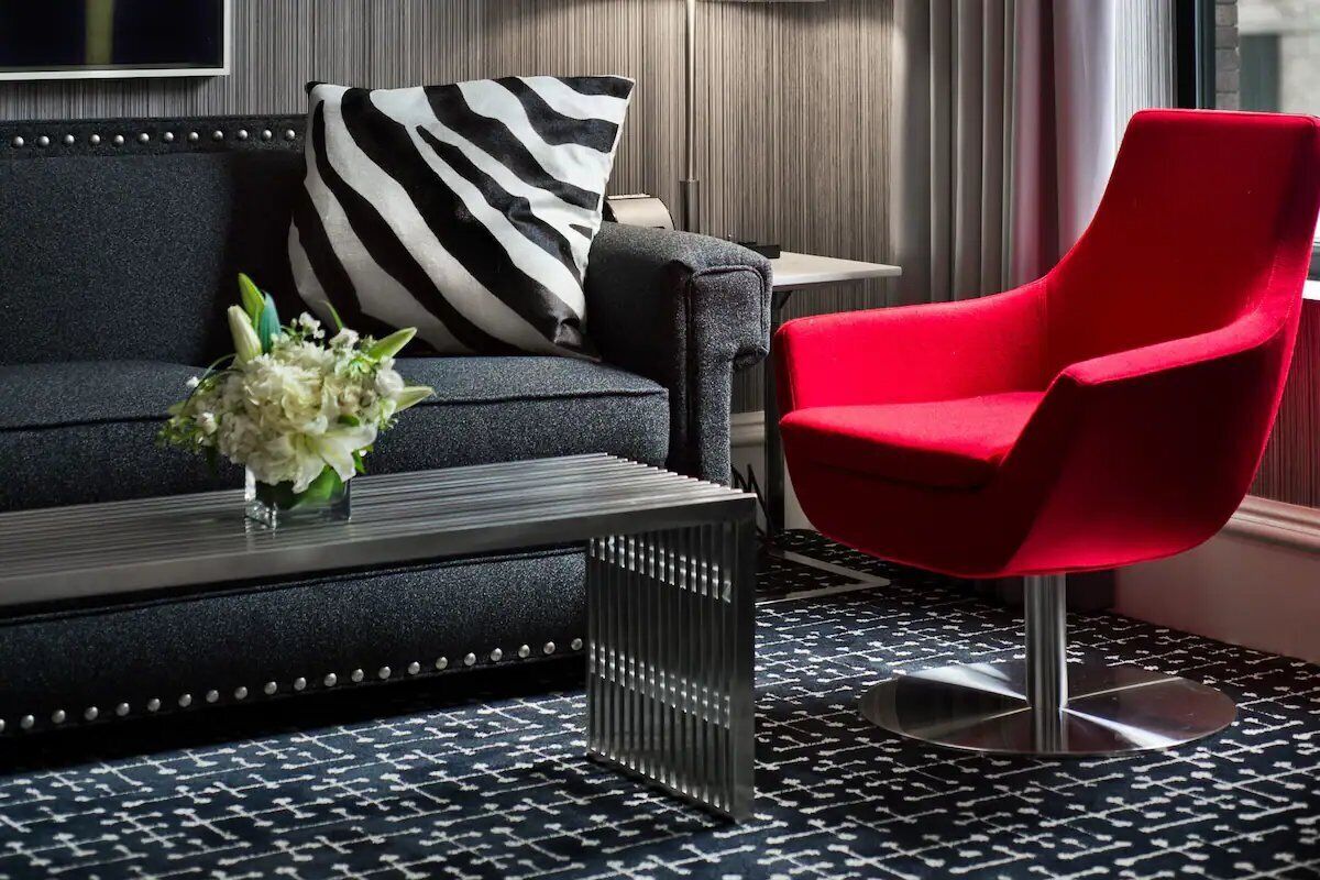 Un salón moderno con sofá, sillón rojo y una mesita de centro.