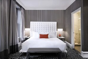 Ein Hotelzimmer mit einem großen Bett, einem Kopfteil, Nachttischen und einer Badezimmertür.