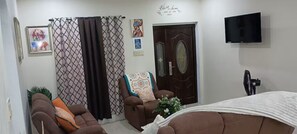 A living room with a sofa, a chair, a television, and a door. - Ocean Breeze Oasis (Montego Bay)