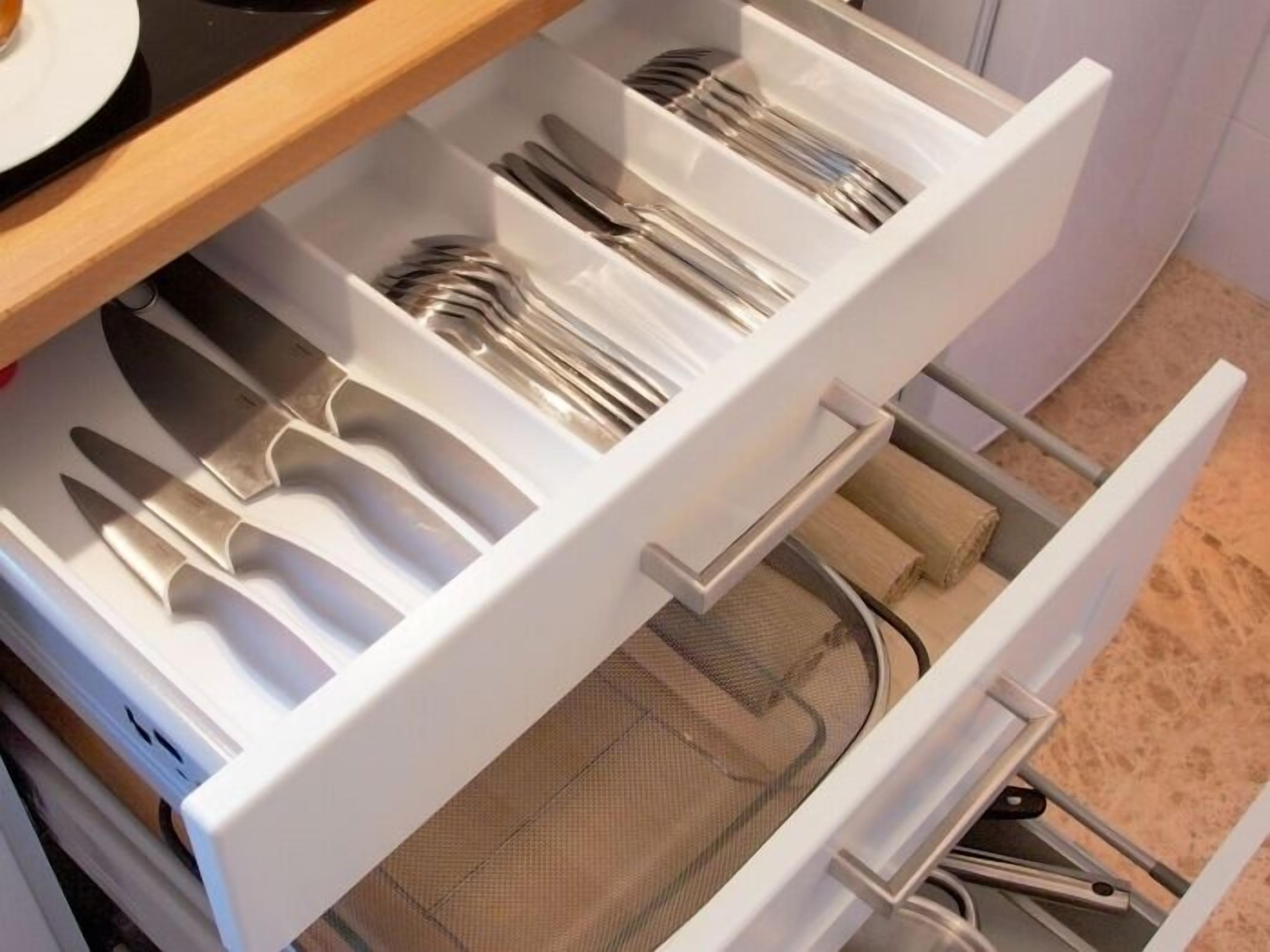 Un cajón de cocina con utensilios y un colador de malla.
