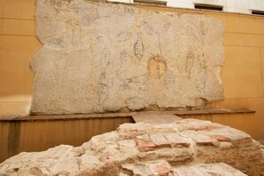 Eine hohe Steinmauer mit alten Schnitzereien, eine Holzplattform und ein Stapel Ziegelsteine.