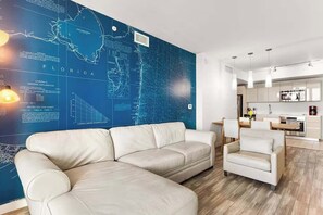Ein modernes Wohnzimmer mit einer großen Wandkarte, einem Sofa, einem Couchtisch und einer Küchenzeile.