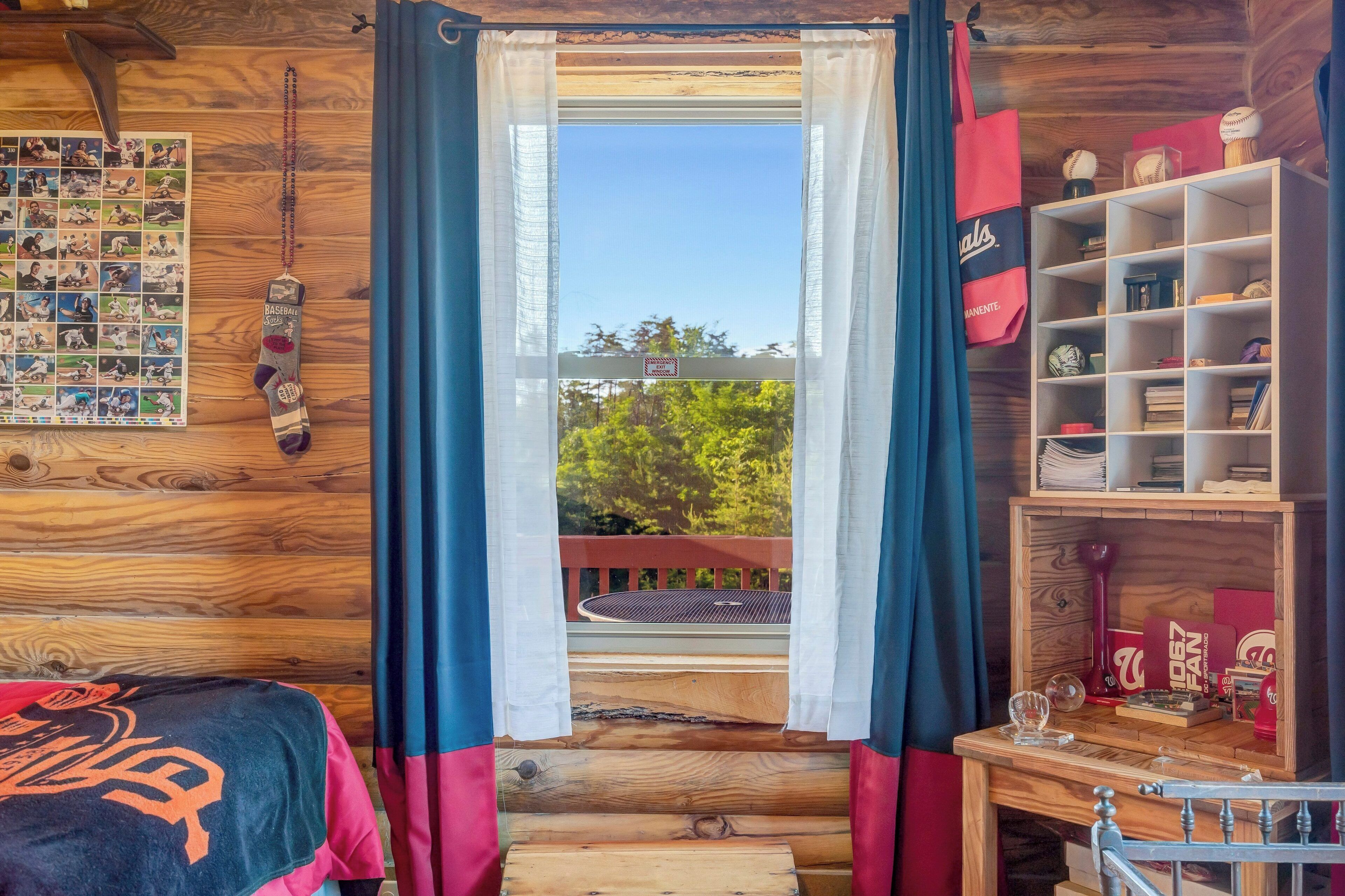 Een kamer met een houten wand, een raam met gordijnen, een plank met souvenirs, en een bed met dekbed.