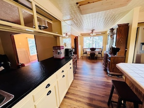 Eine Küche mit schwarzer Arbeitsplatte, Holzschränken und einem Essbereich mit Tisch und Stühlen.