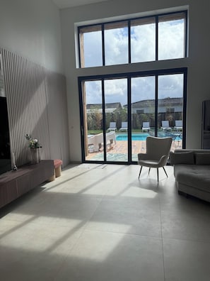 A spacious living room with a large sliding glass door leading to a backyard with a pool and outdoor furniture. - ⭐ Villa Aetheria: Large Pool, Movie Theater—An Exceptional Villa Near Bordeaux (Ambarès-et-Lagrave)