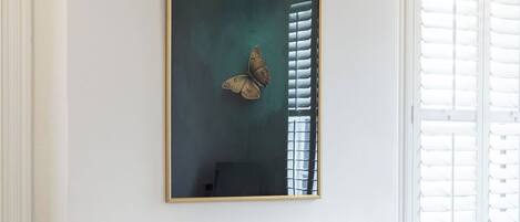 A room with a fireplace, a bed with a blanket, a chair, and a wall-mounted painting.