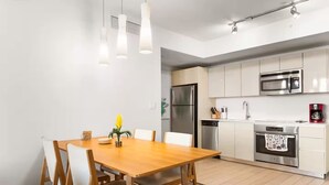 Een moderne keuken met roestvrijstalen apparatuur, een houten eettafel en hanglampen.