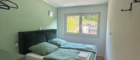A room with a bed, a window, and a wall-mounted light fixture.