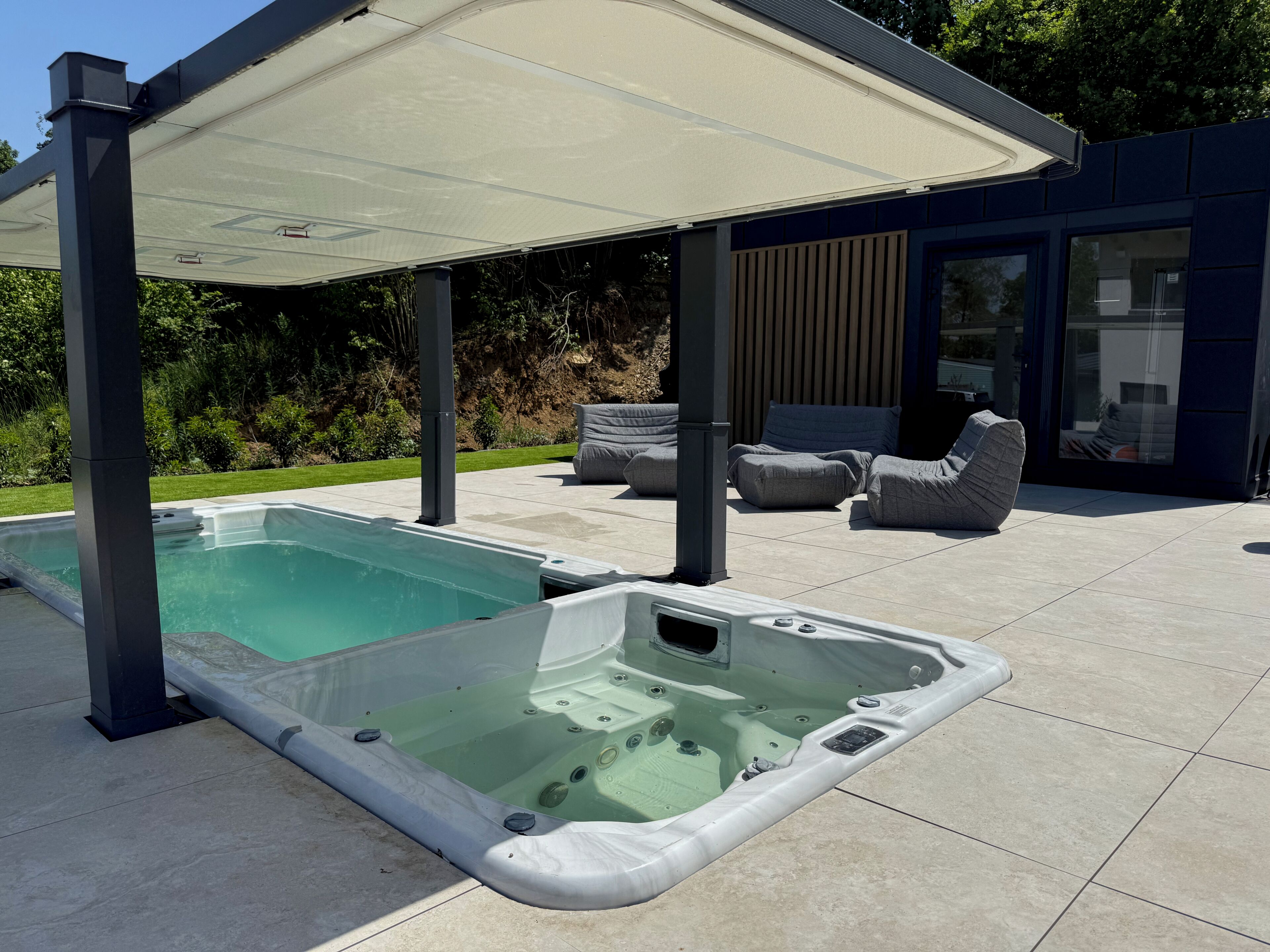 A swimming pool with a hot tub, outdoor seating, and a covered patio area.