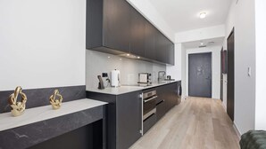Eine moderne Küche mit dunklen Schränken, einer Marmorarbeitsplatte und einem eingebauten Backofen.