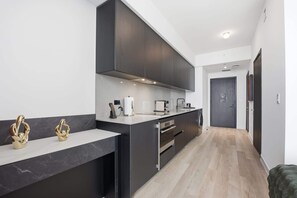 Eine moderne Küche mit dunklen Schränken, einer Marmorarbeitsplatte und einem eingebauten Backofen.