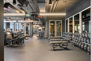 A gym with exercise equipment, dumbbells, and a large window. - Experience The Brand New E11EVEN Residences (Miami)
