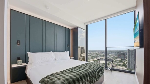 A modern bedroom with a large bed, a view of the city, and a balcony. - Experience The Brand New E11EVEN Residences (Miami)