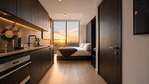 Una cocina moderna con horno empotrado, zona de comedor con mesa y sillas, y un ventanal con vistas a la ciudad.