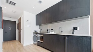 A modern kitchen with dark cabinetry, a built-in oven, and a stainless steel sink. - Stunning Studio Suite At The E11EVEN Residences (Miami)
