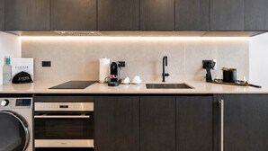 Een moderne keuken met donkere houtkleurige kastjes, een roestvrijstalen spoelbak, een koffieapparaat en een vaatwasser.