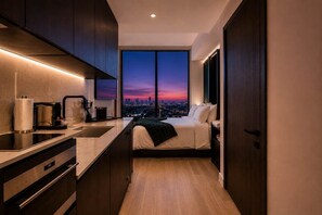 A modern hotel room with a kitchen, a bed, and a large window with a city view. - Rooftop Pool Condo in Downtown Miami w/ City Views (Miami)