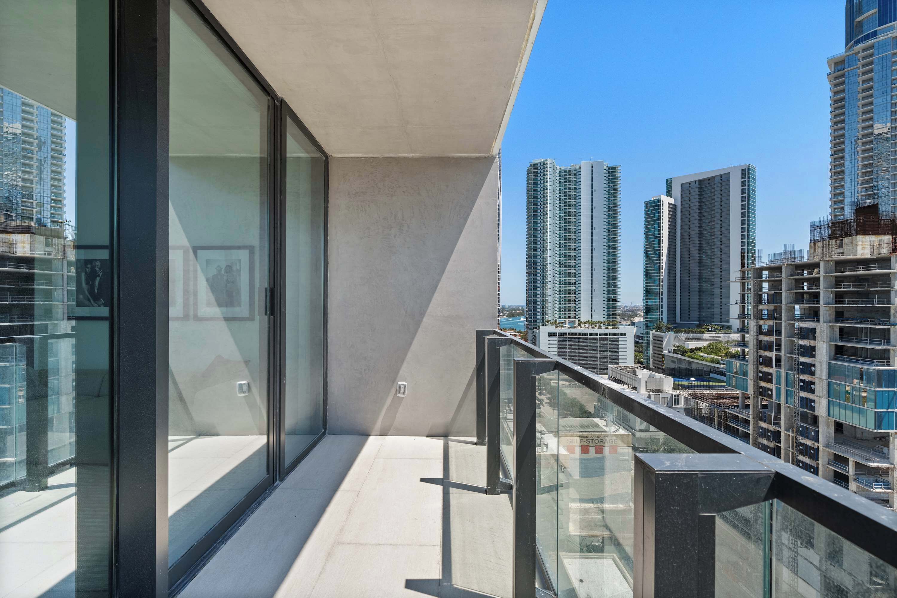 A balcony with a city view, glass doors, and a metal railing.