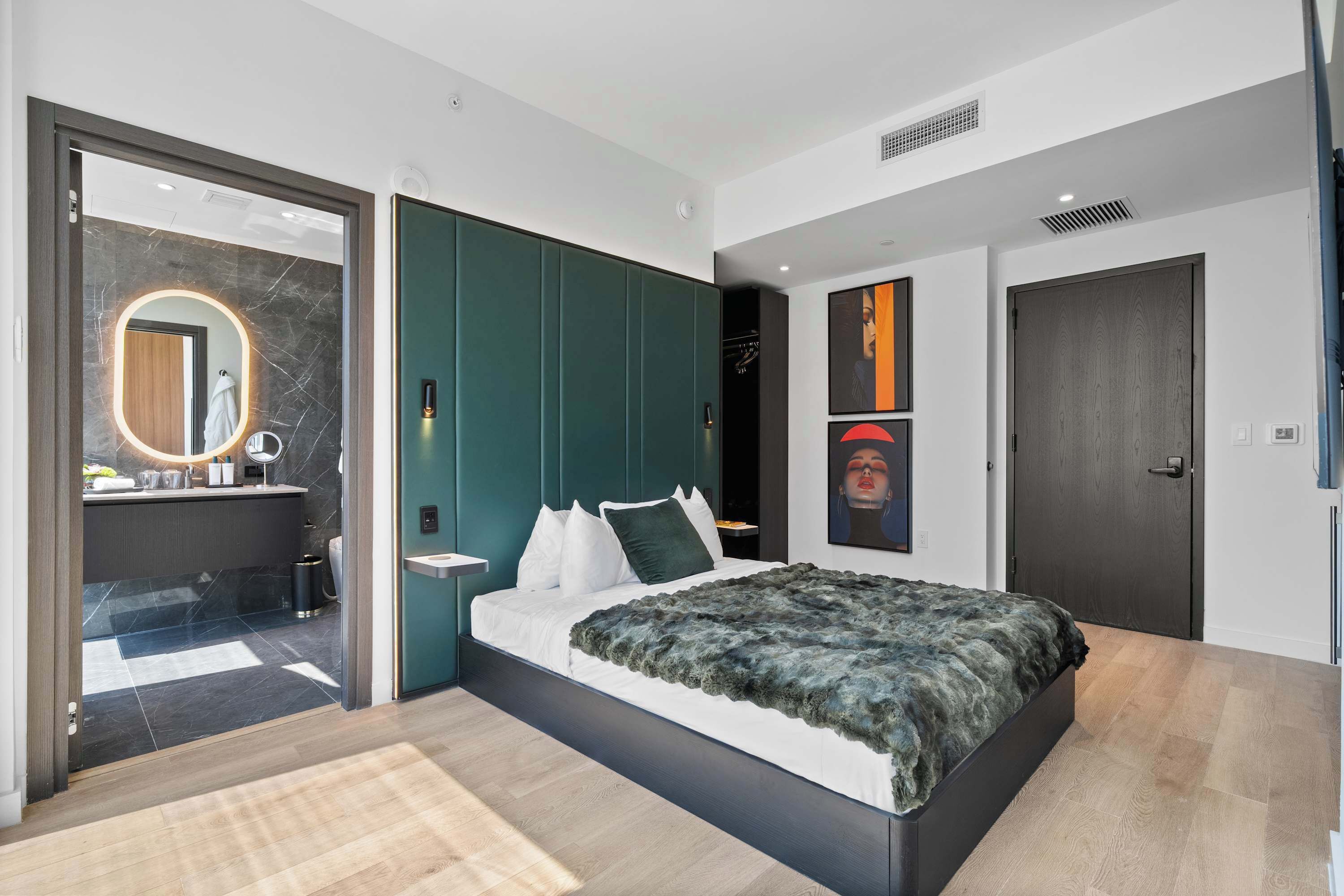 Ein modernes Schlafzimmer mit einem großen Bett, einem begehbaren Kleiderschrank und einem Badezimmer mit Marmor-Waschtisch.