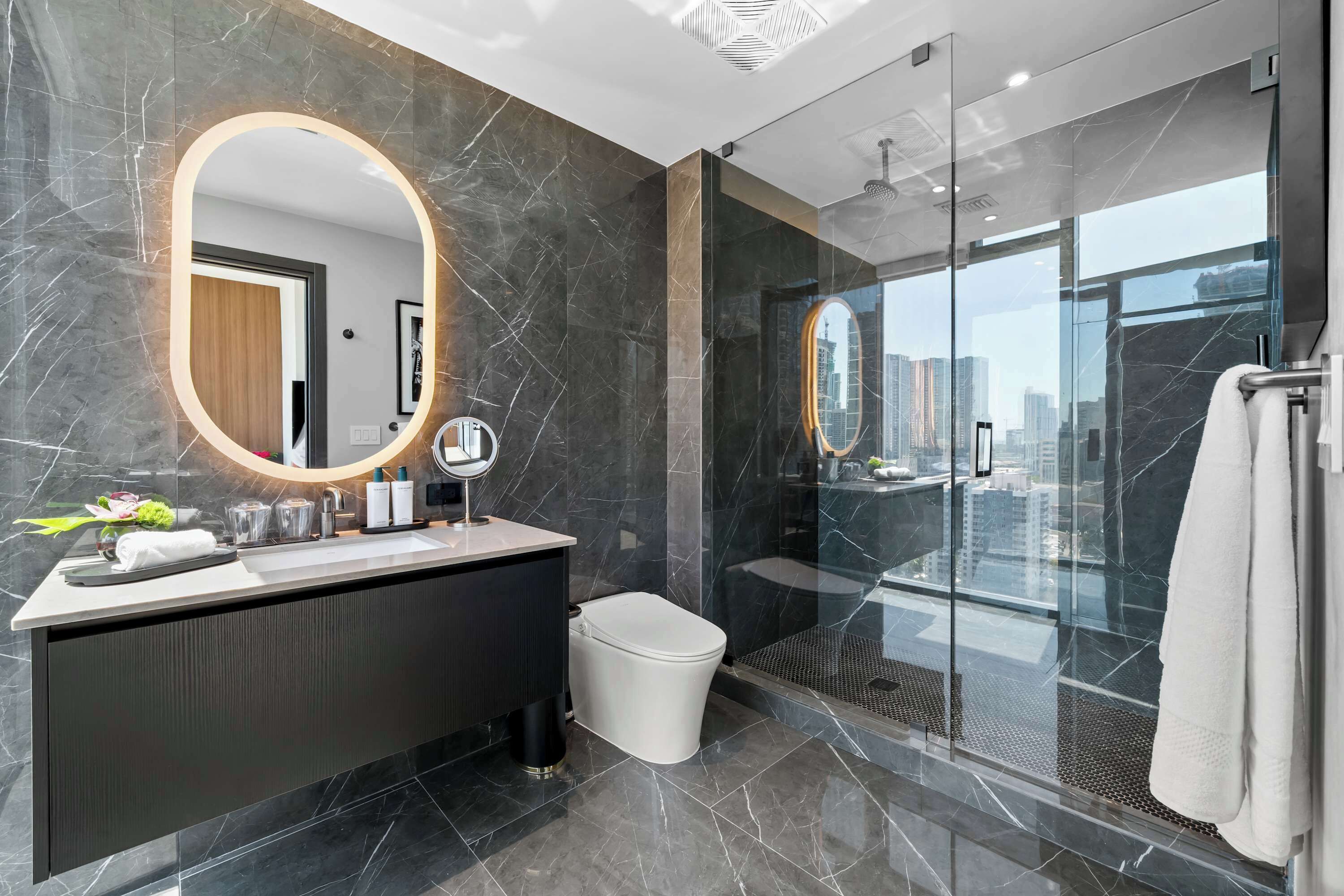 Une salle de bain moderne avec un meuble-lavabo en marbre, un grand miroir et une douche à parois de verre.