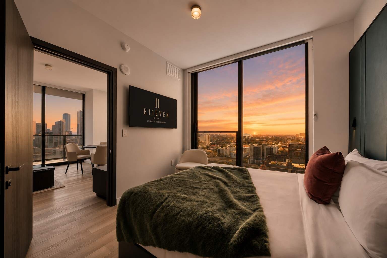 A modern hotel room with a large bed, a city view, a desk, and a chair.