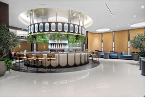 Eine moderne Bar mit kreisförmigem Design, Sitzgelegenheiten und Pflanzen.