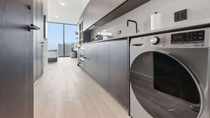 Eine moderne Küche mit integriertem Wasch- und Trockner, großem Fenster und minimalistischem Design.