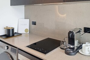 A modern kitchen with a built-in induction cooktop, a coffee machine, and a minimalist design. - Indulge at E11EVEN Private Pool & Elite Gym (Miami)