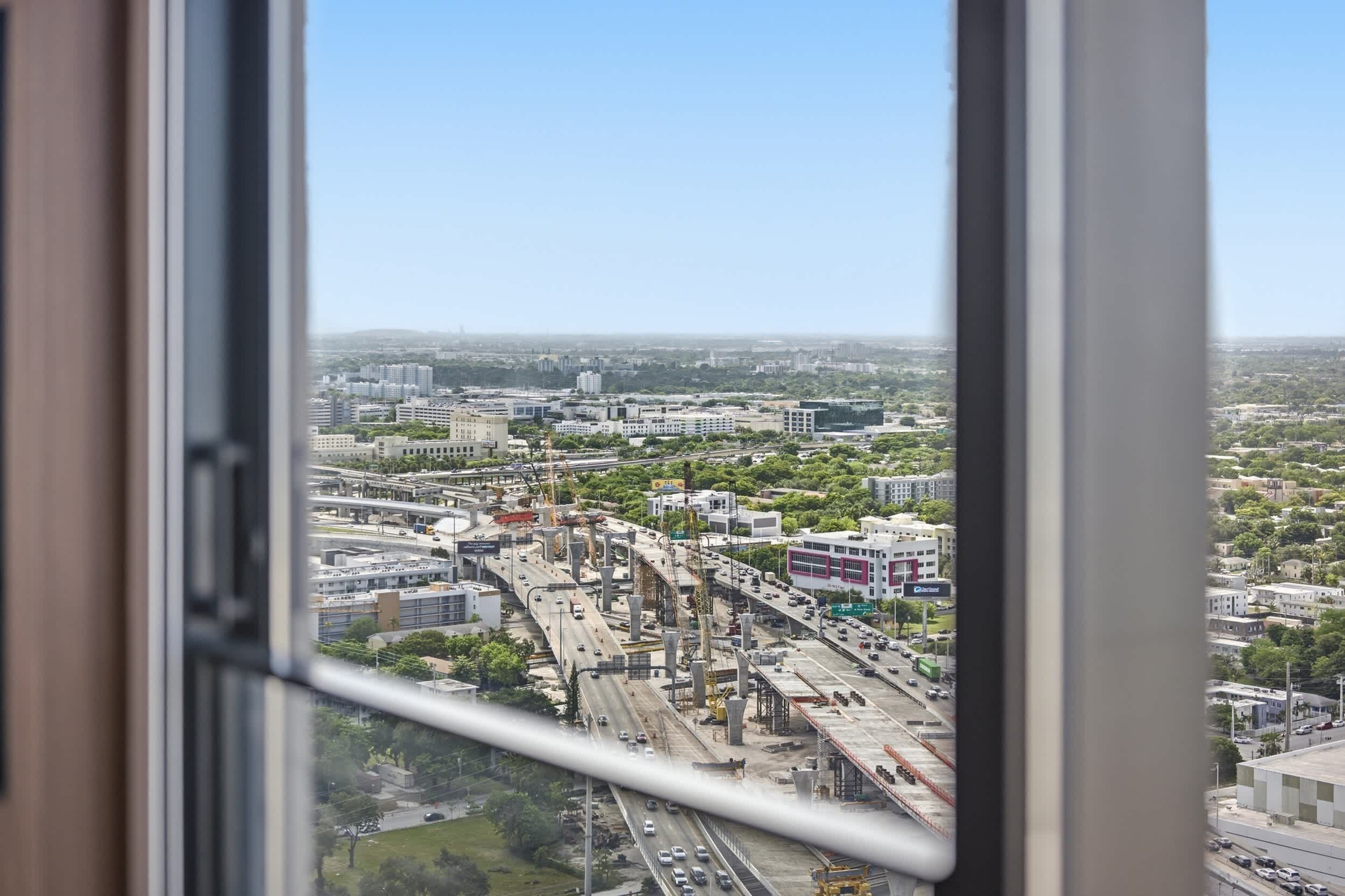 A cityscape with a highway and buildings, viewed from a window.
