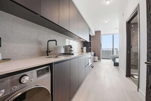 A modern kitchen with a built-in dishwasher, a coffee machine, and a large window offering a view of the city. - Luxury Downtown Miami Suite Brand New Building (Miami)