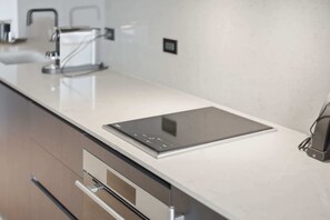 Et moderne køkken med en integreret induktionskogetop, rustfrie stål-apparater og et minimalistisk design.