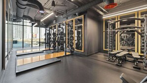 Ett gym med utrustning för styrketräning, speglar och ett stort fönster.