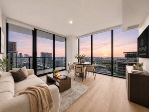 Uma sala de estar moderna com uma janela ampla, um sofá, uma mesa de centro e um espaço de jantar com cadeiras.