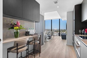 A modern kitchen with a bar area, large windows, and a city view. - Brand New Adjoining Suite The E11EVEN Residences (Miami)