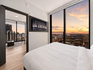 A modern hotel room with a large bed, a city view through floor-to-ceiling windows, and a framed picture on the wall. - Brand New Adjoining Suite The E11EVEN Residences (Miami)
