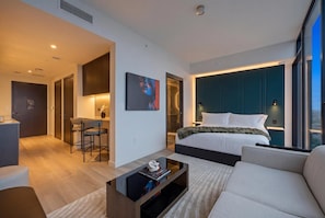 A modern hotel room with a bed, a sofa, a TV on a stand, a desk with chairs, and a large window. - Luxury Downtown Miami Studio with Resort Amenities (Miami)
