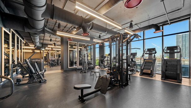 A gym with exercise equipment, large windows, and a view of a cityscape. - Luxury Downtown Miami Studio with Resort Amenities (Miami)