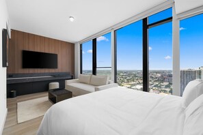 Ein modernes Hotelzimmer mit einem großen Bett, einer Sitzecke, einem Flachbildfernseher und Blick auf die Stadt.