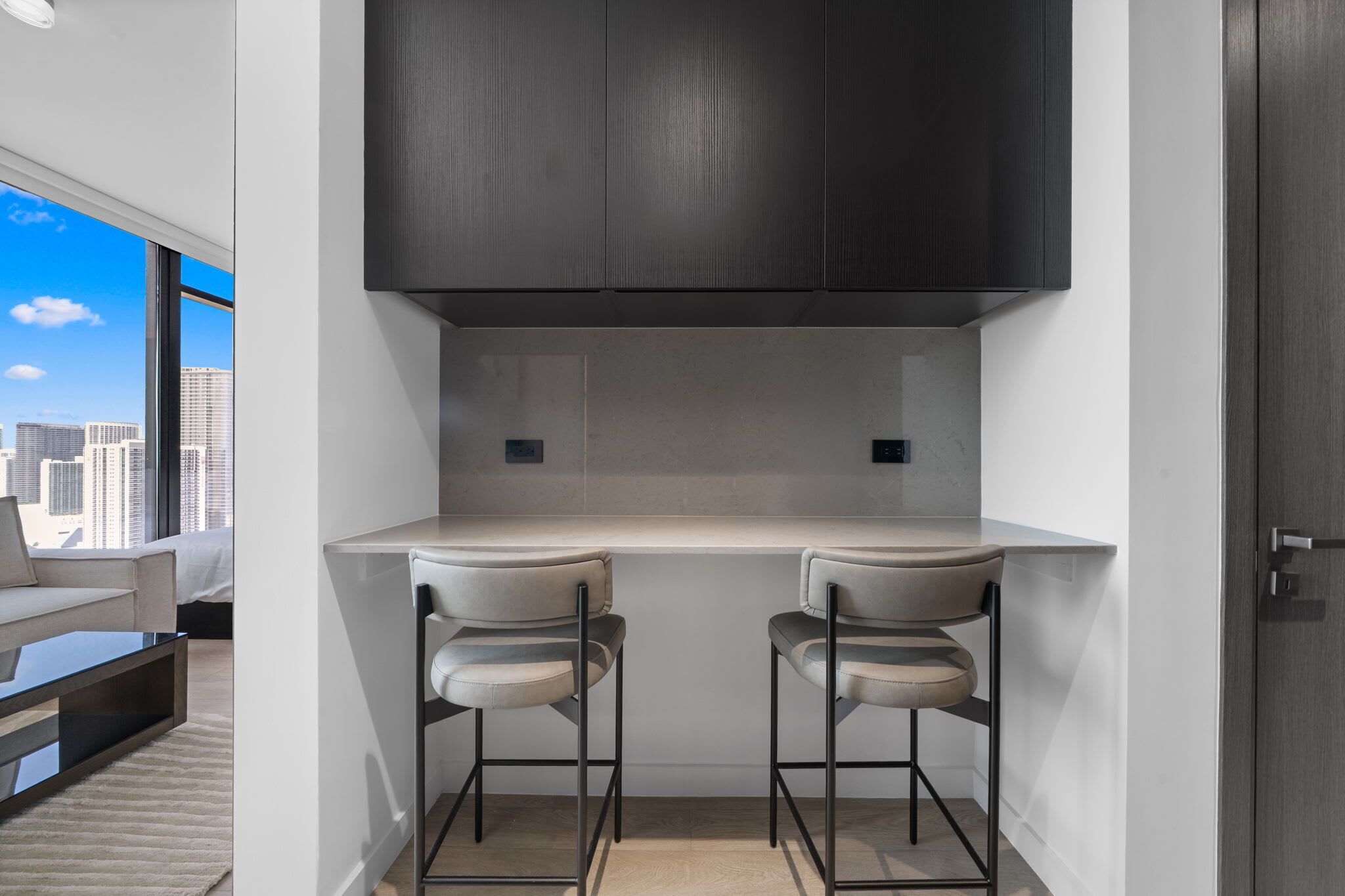 Une cuisine moderne avec deux tabourets de bar, un four encastré et une vue sur la ville.