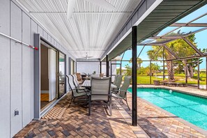 Eine überdachte Terrasse mit Pool, Gartenmöbeln und Blick ins Freie.